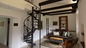 A spacious living area with a spiral staircase, a leather sofa, and a patterned rug.