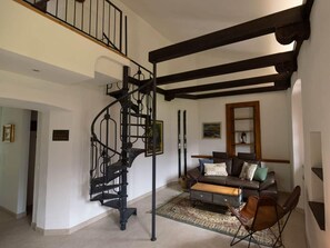 Un'ampia zona giorno con una scala a chiocciola, un divano in pelle e un tappeto decorato.
