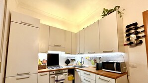 Une cuisine de taille réduite, avec des meubles blancs, une cuisinière à gaz, un four à micro-ondes et un évier.