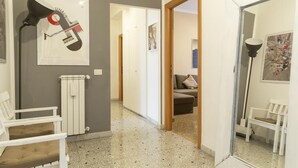 Un couloir avec un radiateur, une chaise blanche et une affiche accrochée au mur.
