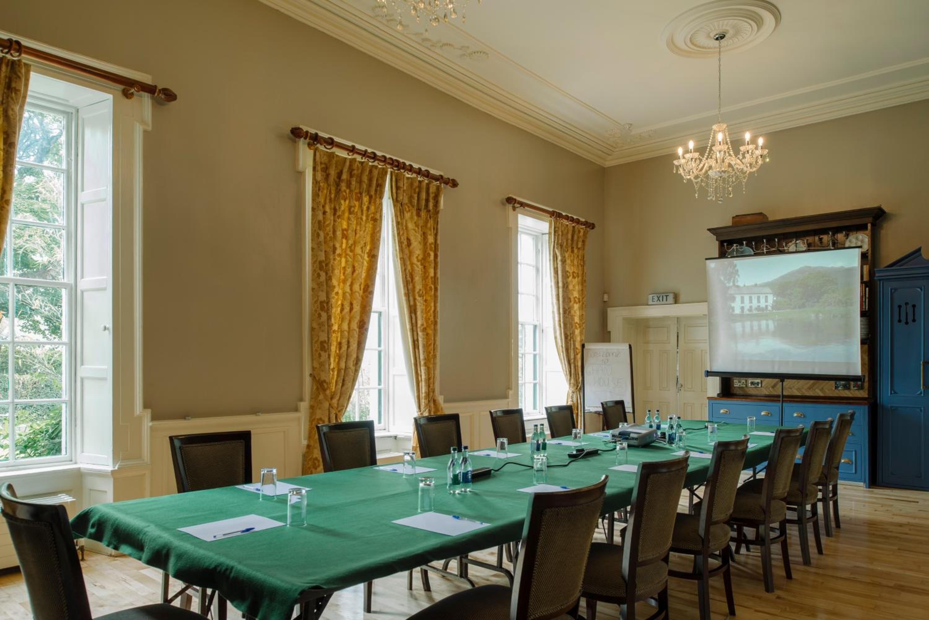A conference room with a long table, chairs, a projector screen, and a whiteboard.
