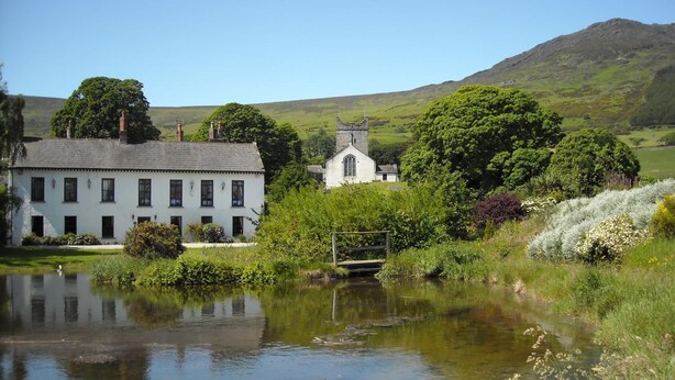 A white building with a stone tower, a pond, and lush greenery. - Ghan House Carlingford (Carlingford)