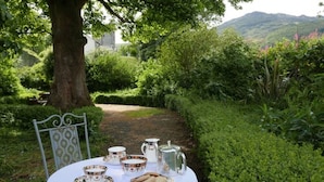 A table set outdoors with tea cups, a teapot, and a plate of cookies. - Ghan House Carlingford (Carlingford)