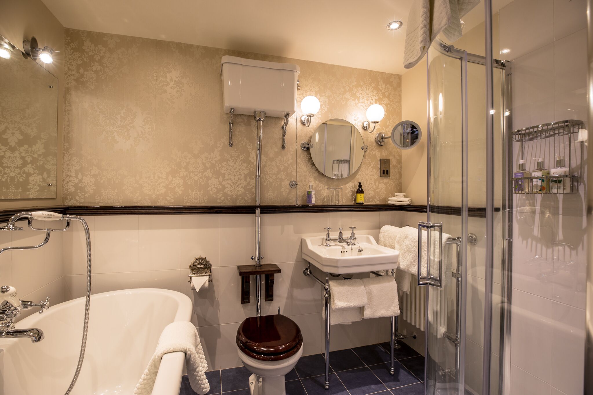 A bathroom with a bathtub, toilet, sink, and glass-enclosed shower.