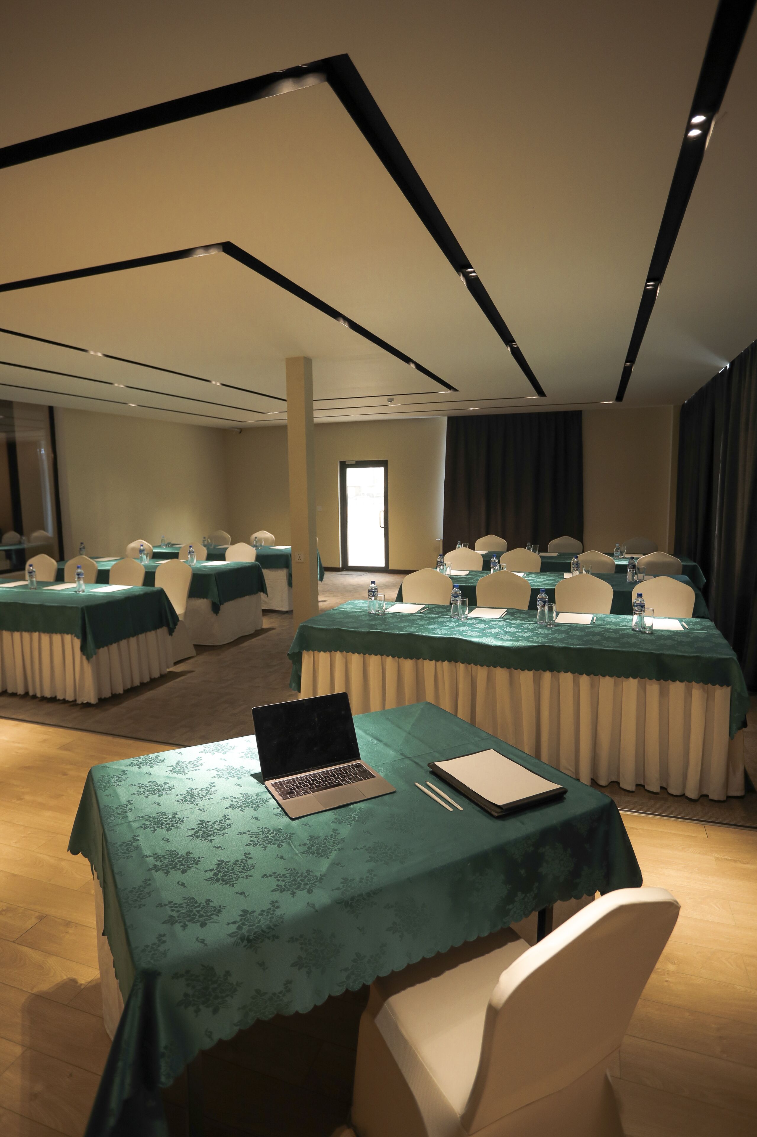 A conference room with tables set for meetings, equipped with laptops and water bottles.