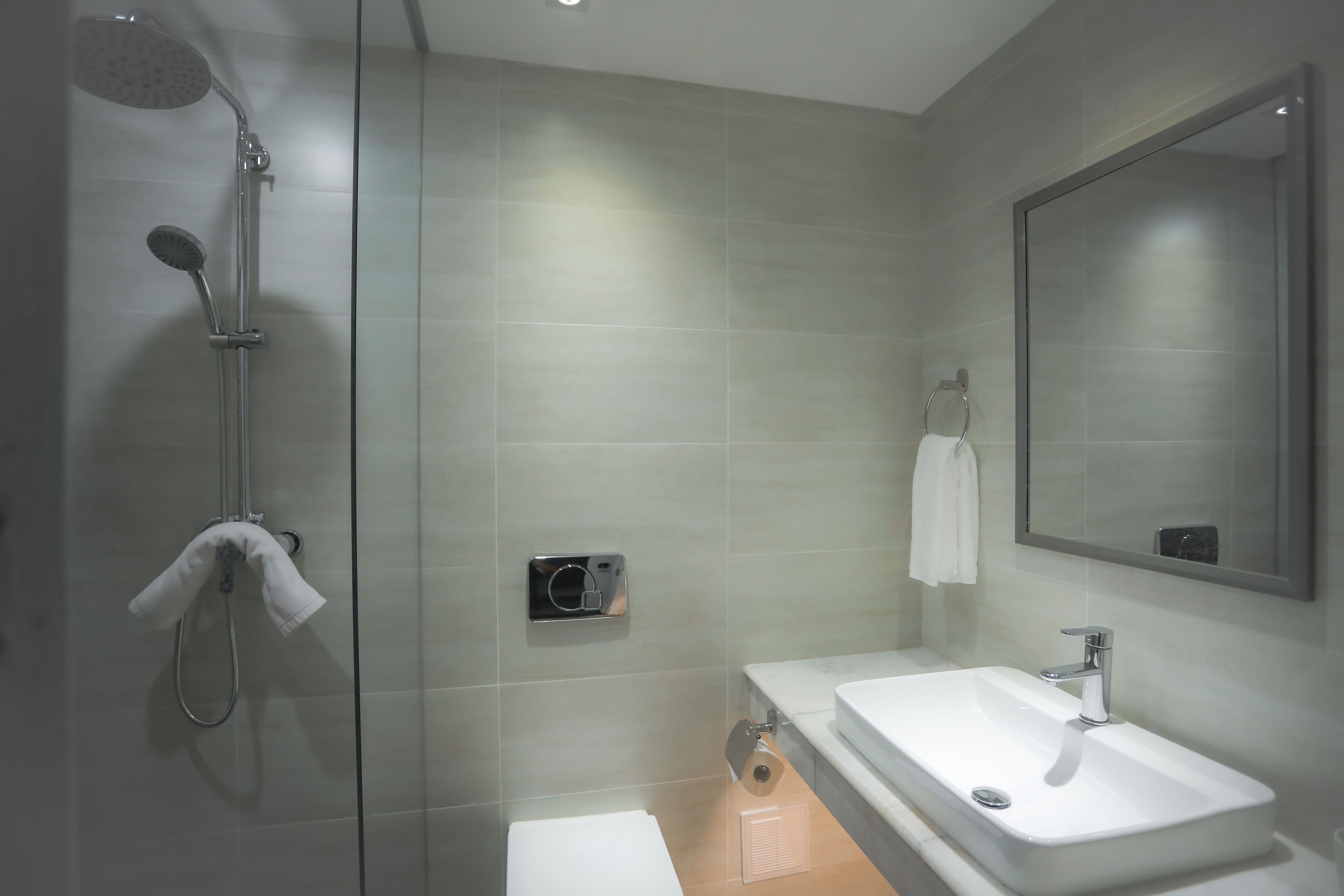 A modern bathroom with a glass-enclosed shower, a white sink, and a large mirror.