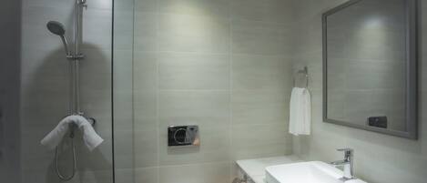 A modern bathroom with a glass-enclosed shower, a white sink, and a large mirror.