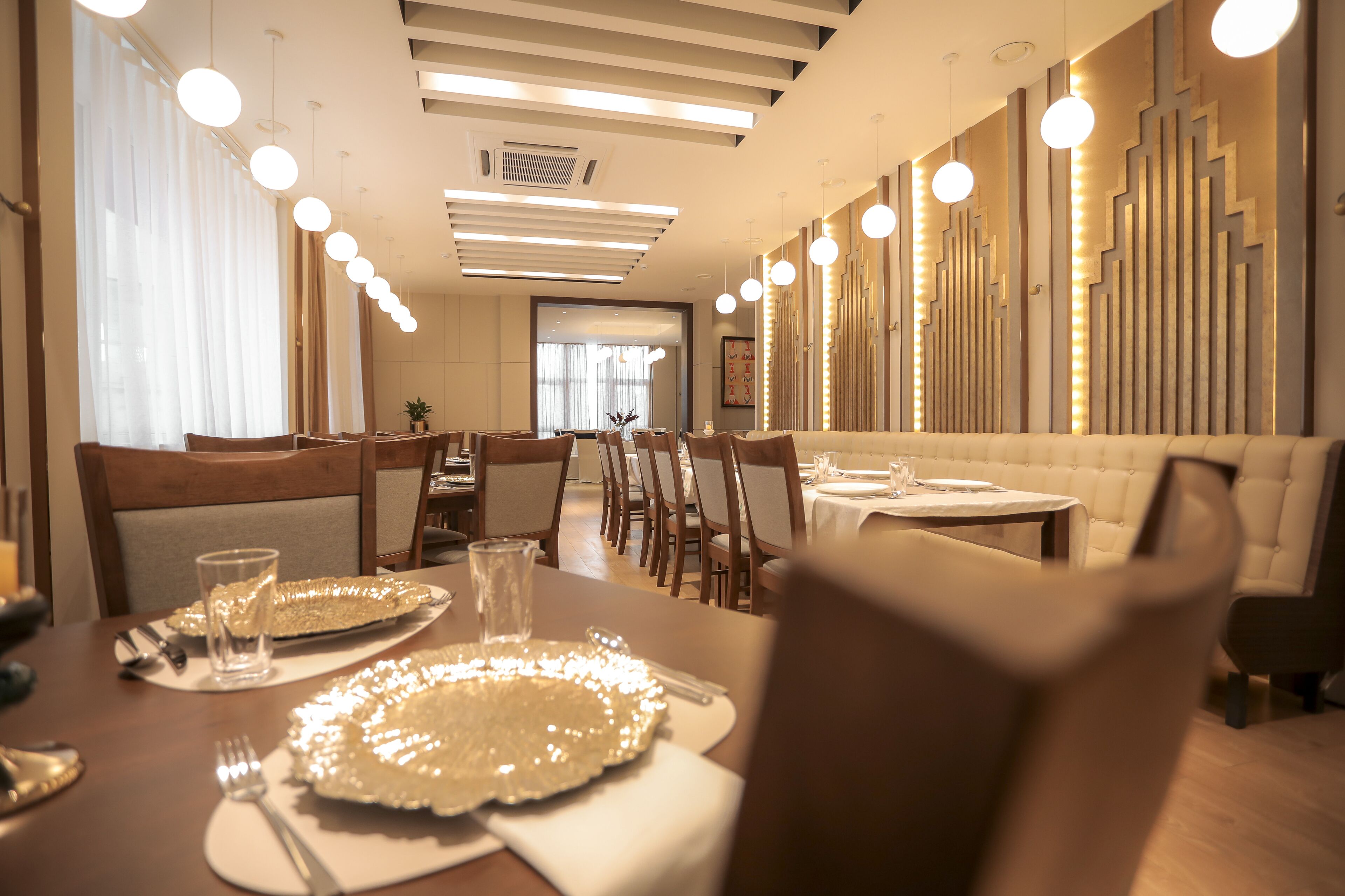 A modern dining area with a long table, multiple chairs, and pendant lighting.