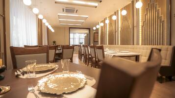A modern dining area with a long table, multiple chairs, and pendant lighting.