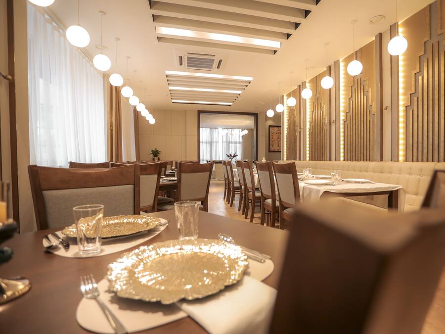 A modern dining area with a long table, multiple chairs, and pendant lighting.