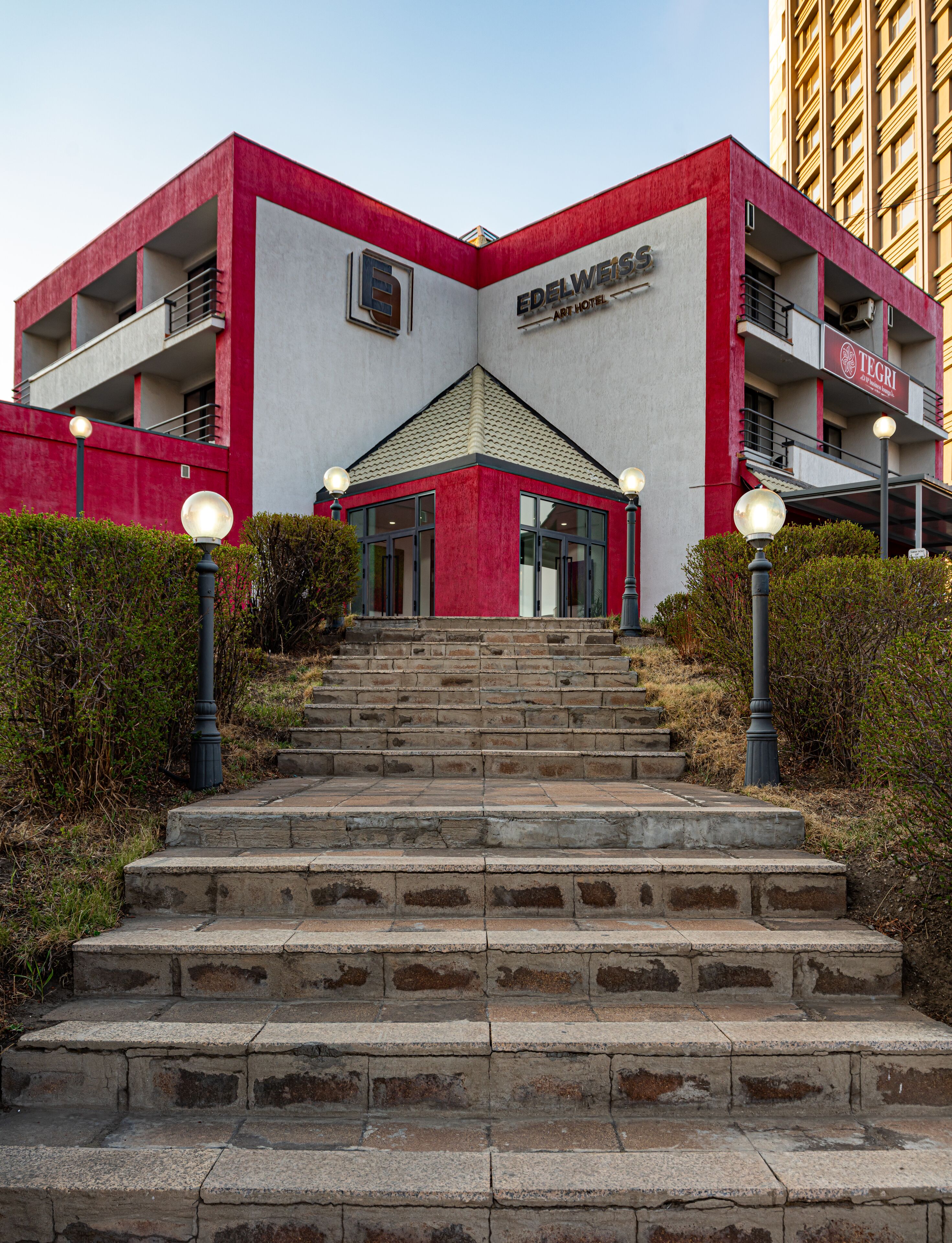 A building with a red and white facade, a central entrance, and a staircase leading up to it.