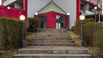 A building with a red and white facade, a central entrance, and a staircase leading up to it.