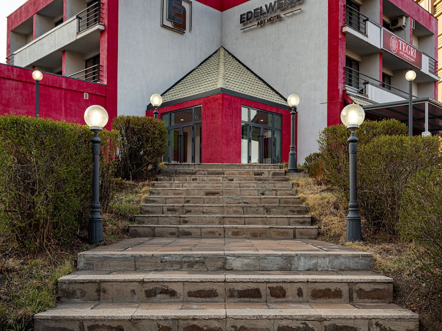 A building with a red and white facade, a central entrance, and a staircase leading up to it.