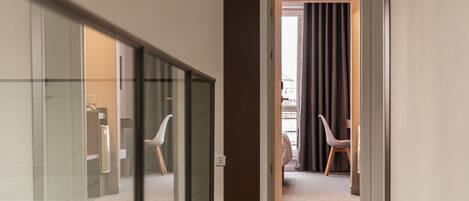 A hotel hallway with a glass partition, a door marked with the number 309, and two chairs in the adjacent room.