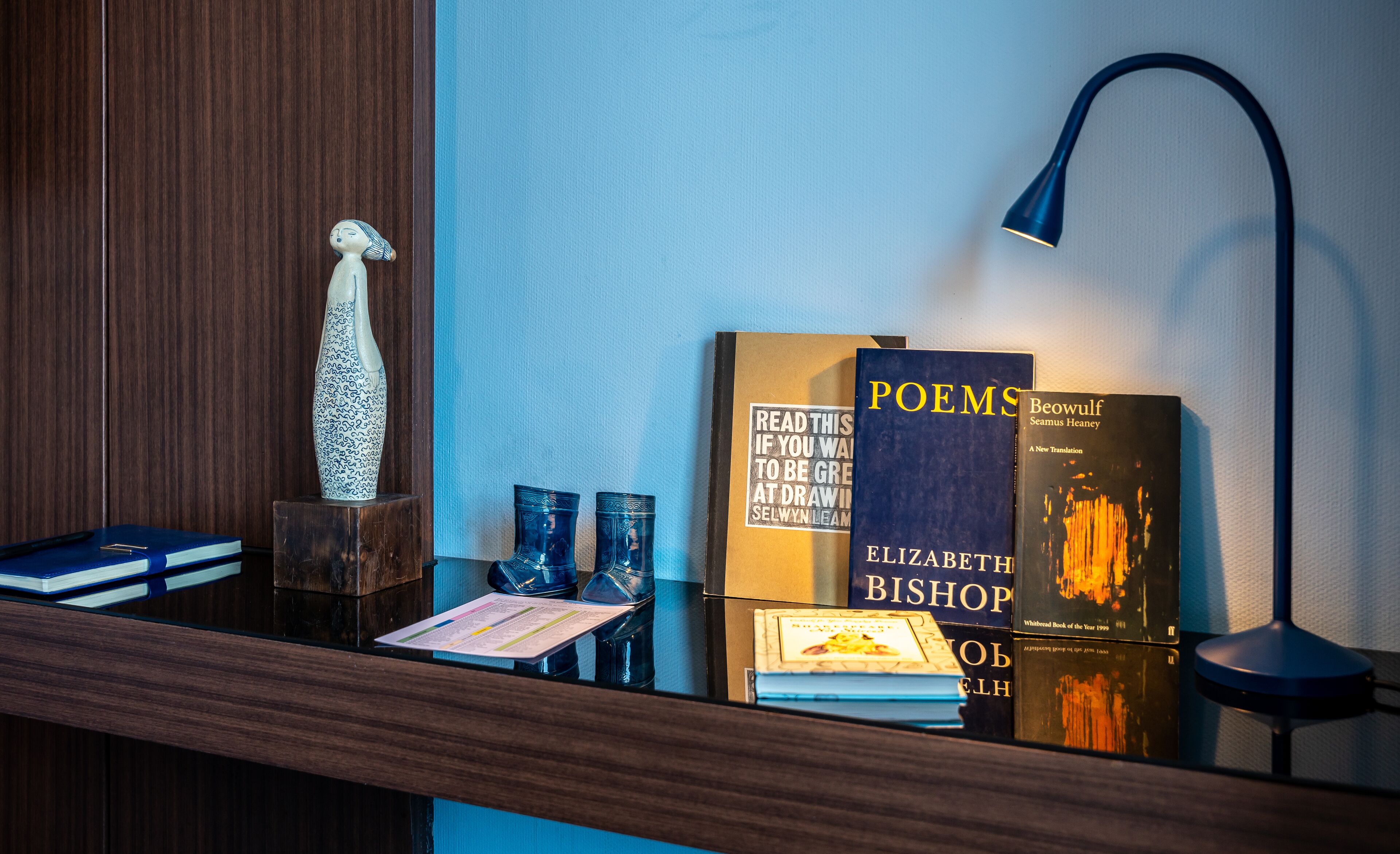 A bookshelf with books, a vase, and a lamp.