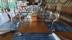Una mesa de comedor preparada con copas de vino, menús y un centro decorativo.