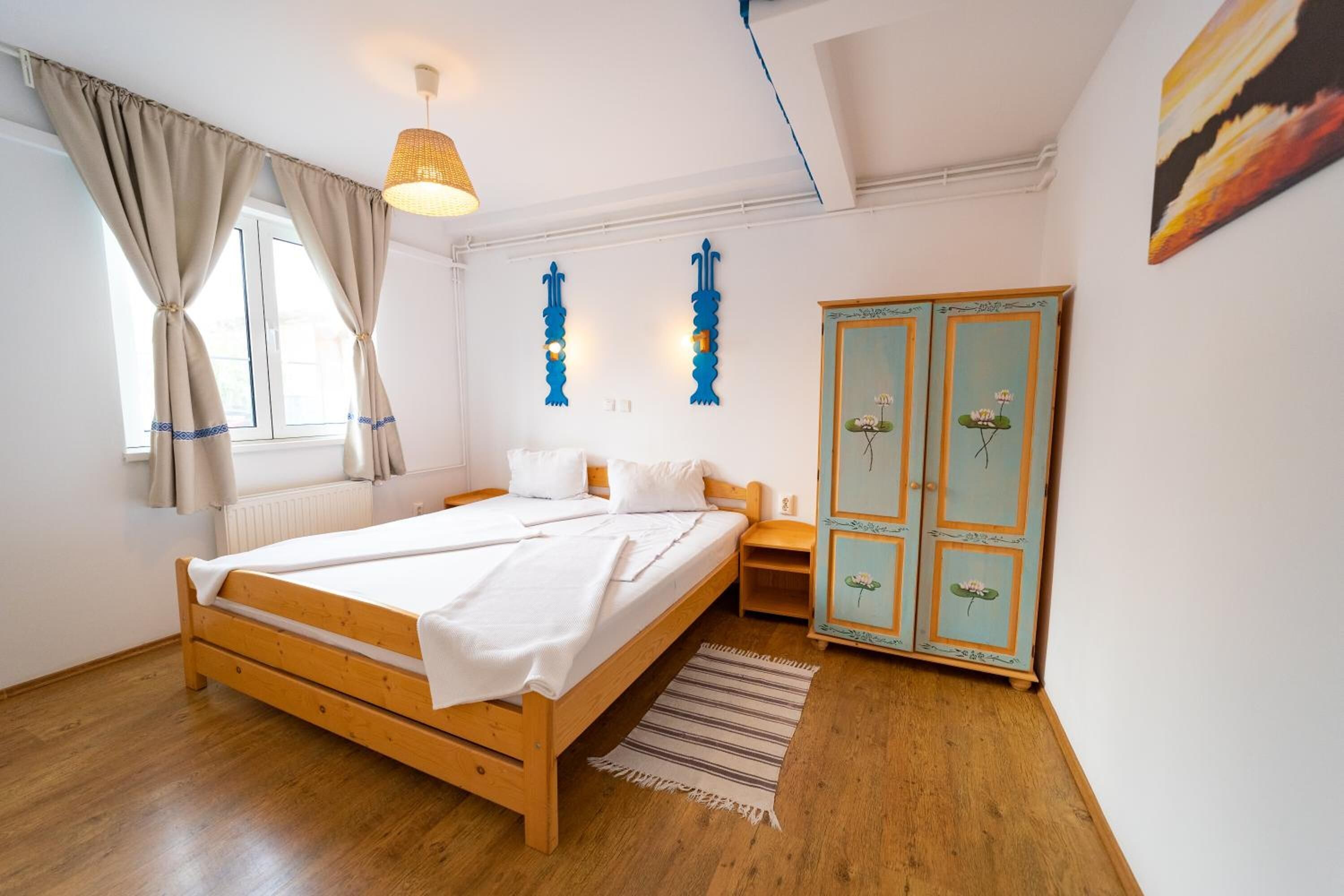 A bedroom with a wooden bed, a nightstand, a wardrobe, and a window with curtains.