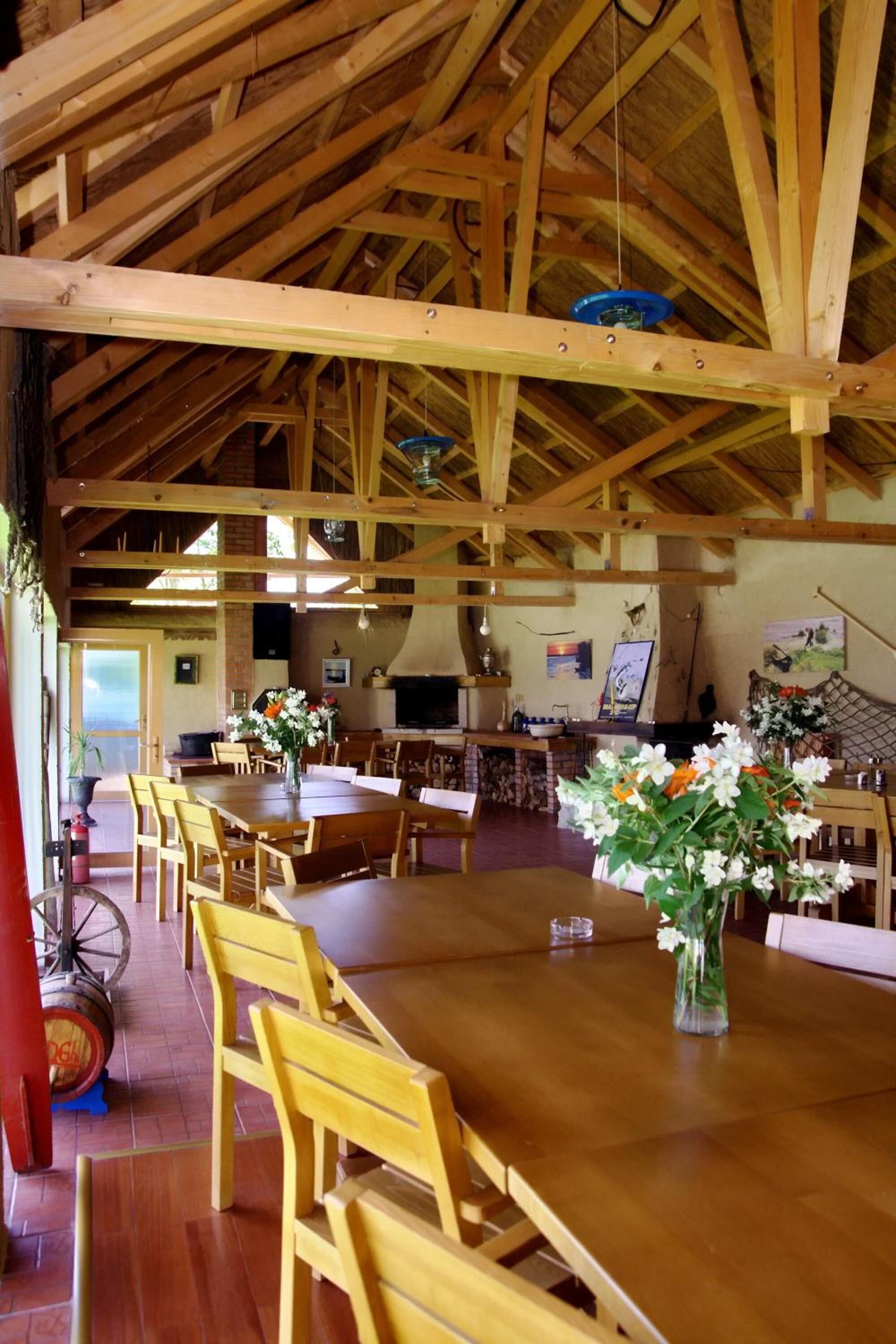 A spacious dining area with wooden tables and chairs, a large wooden ceiling, and a rustic interior.