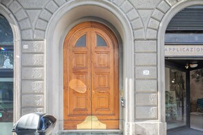 Eine doppelte Holztür mit kleiner Vordach, eingebettet in einen Bogenportal mit dekorativem Steinwerk.