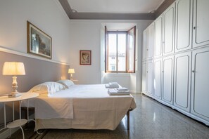 Habitación de hotel con cama, dos mesitas de noche con lámparas, un armario grande y una ventana con vistas.