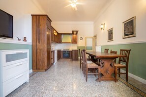 Une cuisine avec des meubles en bois, une table à manger avec des chaises, un four encastré et un ventilateur de plafond.