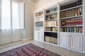 A room with a large bookshelf, a patterned rug, and a door with curtains.
