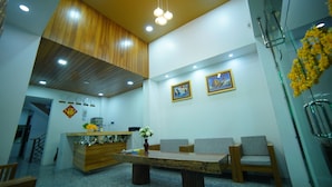 Zona de recepción con mostrador de madera, área de espera con sillas, techo de madera y una pared con dos cuadros enmarcados.