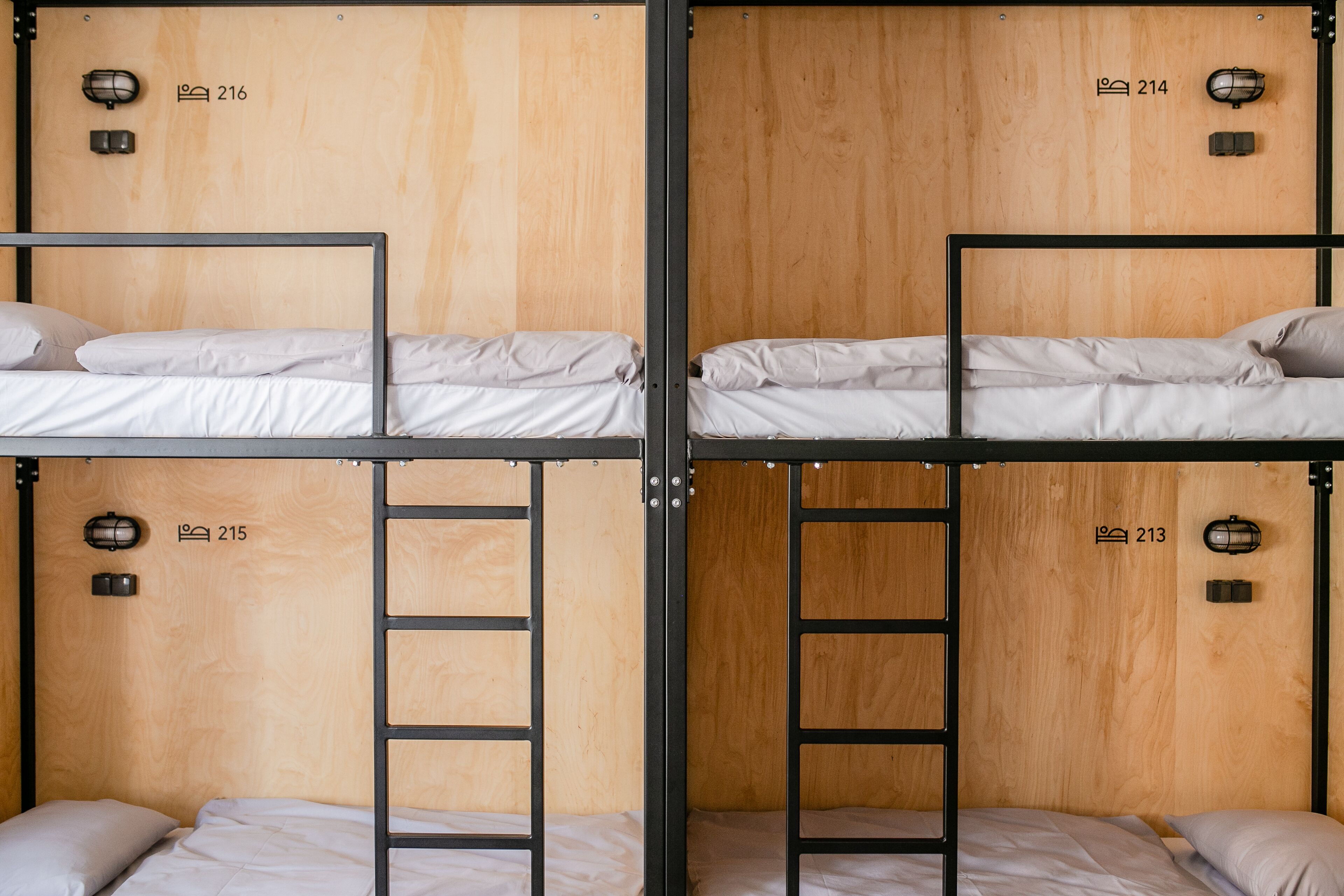 Dormitorio con literas, paredes de madera, camas numeradas y lámparas fijadas a la pared.