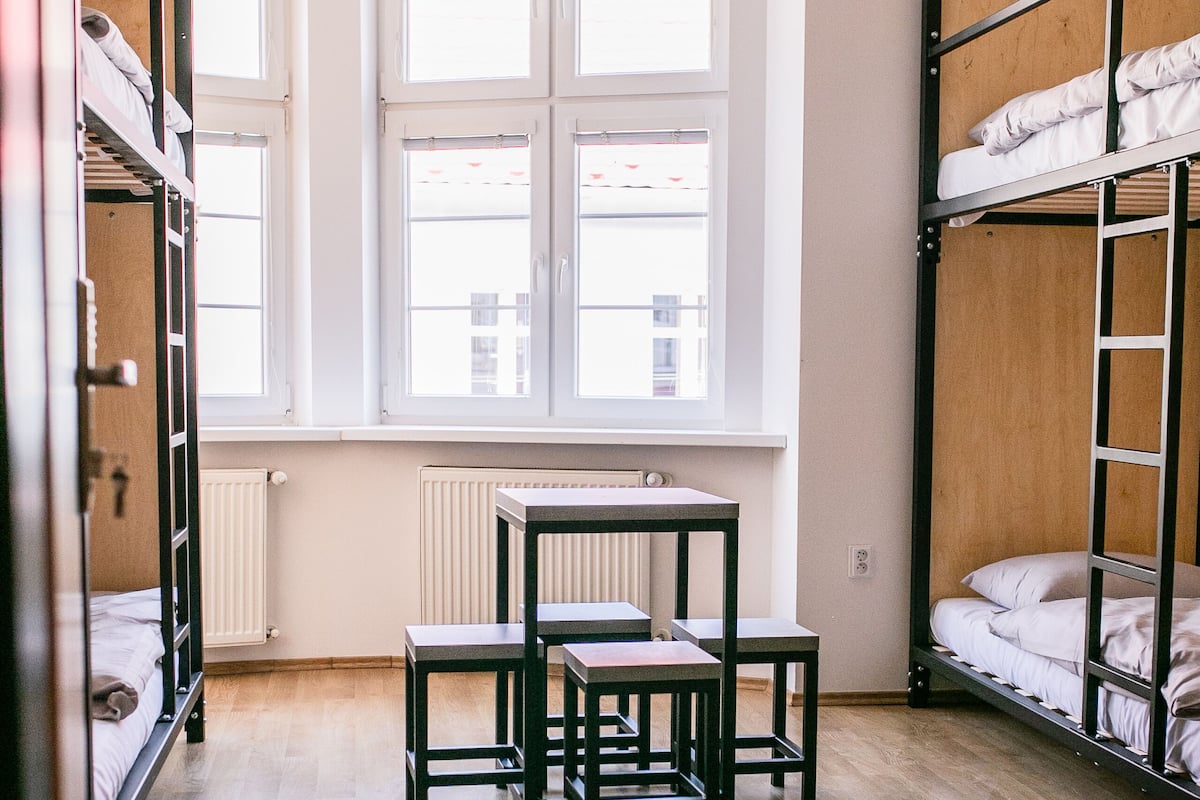 A dormitory room with bunk beds, a table, and chairs.