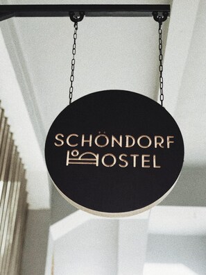 A hanging sign with the text "SCHÖNDORF HOSTEL" and a bed icon, indicating a hostel accommodation. - Schöndorf Hostel (Bratislava)