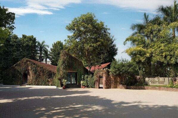 A resort with a stone wall, a red-roofed building, and a sign indicating it's a guesthouse. - The Fern Ranthambhore Forest Resort Sawai Madhopur, Series by Marriott (Sawai Madhopur)