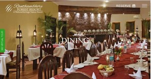 A dining area at Ranthambore Forest Resort with tables set for a meal, surrounded by chairs and tables, and a stone wall in the background. - The Fern Ranthambhore Forest Resort Sawai Madhopur, Series by Marriott (Sawai Madhopur)