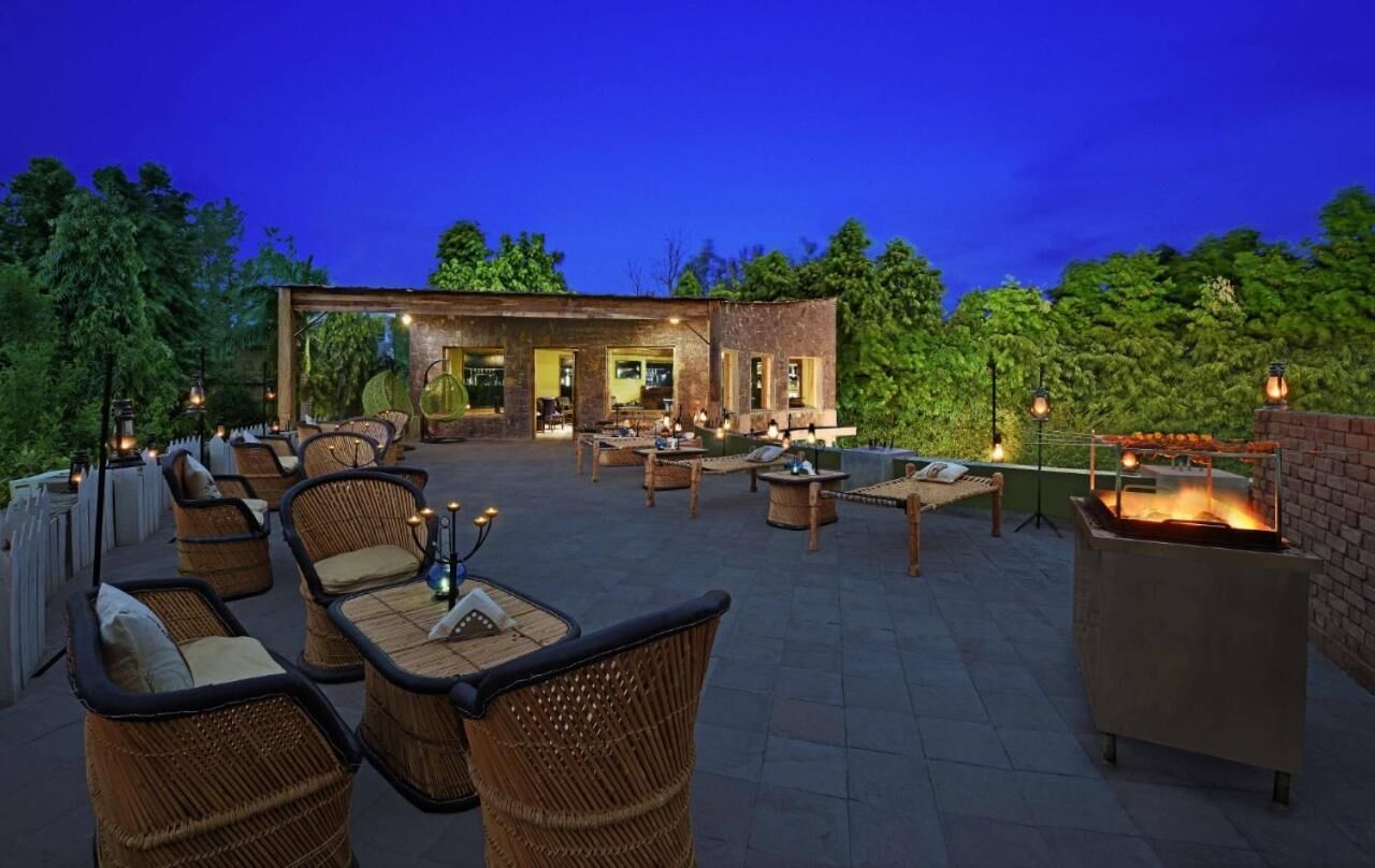 Ein Außenbereich mit einer Terrasse, Korbmöbeln, einer Backsteinmauer und einem Feuerstelle.