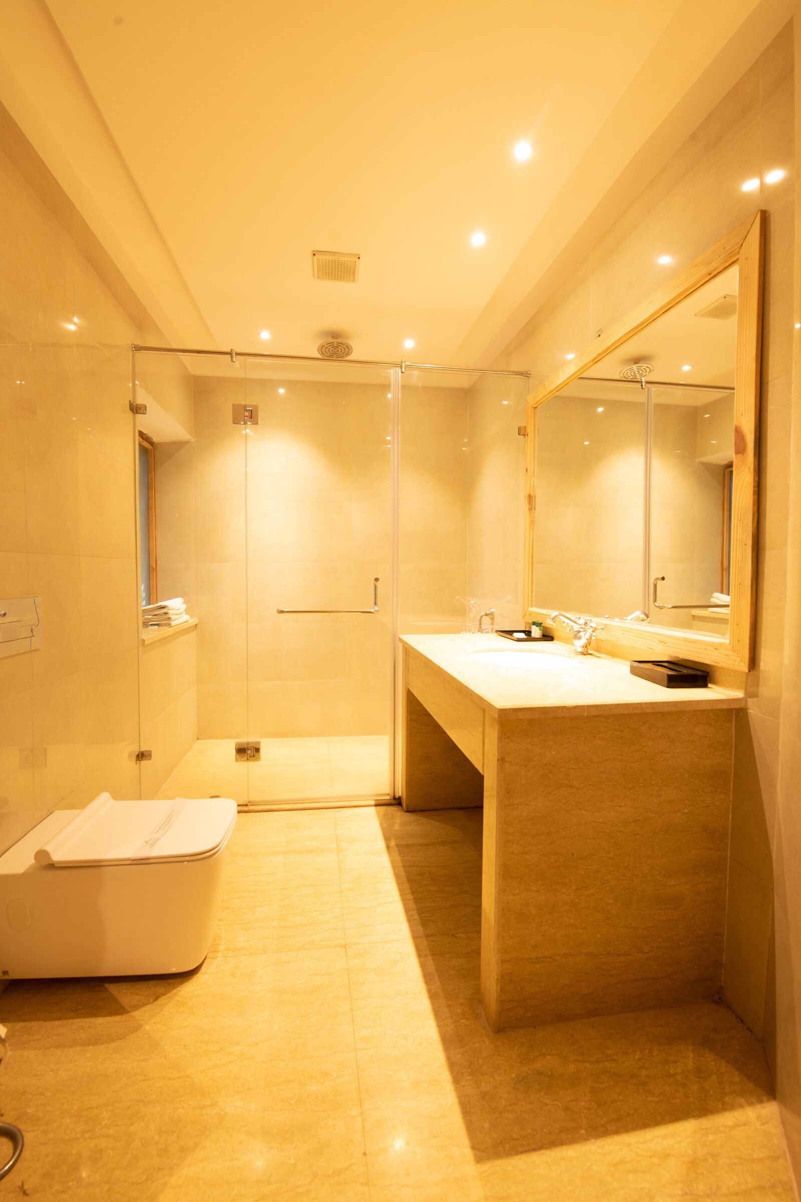 A modern bathroom with a glass-enclosed shower, a large mirror, and a vanity with a sink.