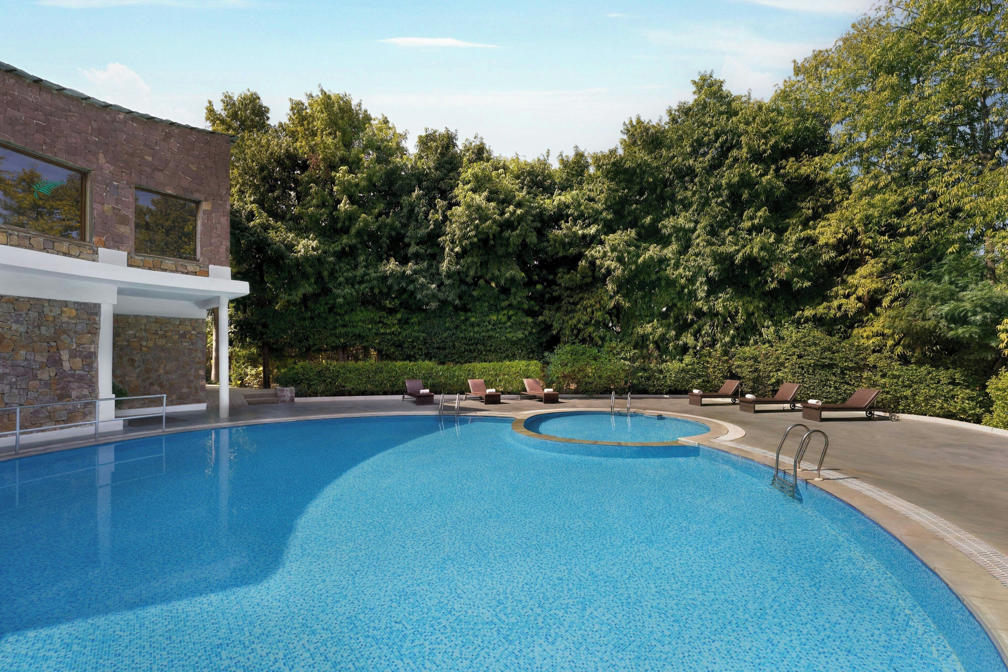 Une piscine avec des chaises longues et un bâtiment en pierre.