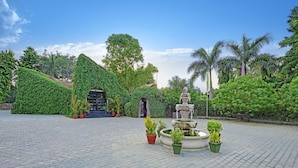 A paved courtyard with a statue, potted plants, and a building entrance surrounded by lush greenery. - The Fern Ranthambhore Forest Resort Sawai Madhopur, Series by Marriott (Sawai Madhopur)