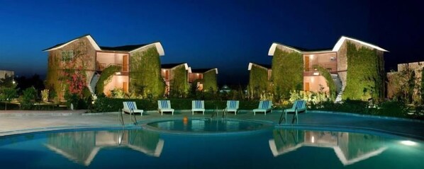 A resort with multiple villas, a swimming pool, and lounge chairs.