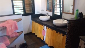 A bathroom with two sinks, a mirror, and a window with blinds. - Three Bungalows in the sun (NOSY-BE,)