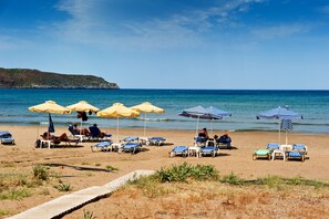 På stranden, solsenger, parasoller og strandbar