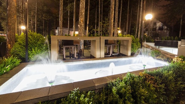 A modern outdoor area with a rectangular pool, two water fountains, and a small building with a flat roof. - Hotel Simsir (Zlatibor)