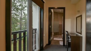 A narrow hallway with a wooden desk and chair, a large window with a view of trees, and a door leading to a bathroom. - Hotel Simsir (Zlatibor)