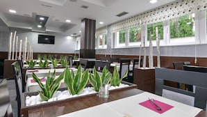 A restaurant with tables set for dining, featuring green plants and white pebbles. - Hotel Simsir (Zlatibor)