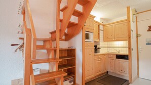 A compact kitchen with wooden cabinets, a microwave, and a built-in bench. - 47m² Duplex in Valmorel, Pets Allowed, Balcony, Near Slopes (Valmorel)