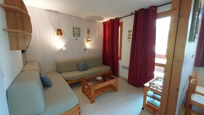 A cozy living room with a sofa, coffee table, and a small table with a lamp. - 47m² Duplex in Valmorel, Pets Allowed, Balcony, Near Slopes (Valmorel)