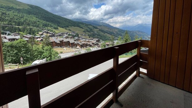 A balcony with a view of a village and mountains. - 47m² Duplex in Valmorel, Pets Allowed, Balcony, Near Slopes (Valmorel)