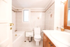 Et badeværelse med badekar, toilet og håndvask.