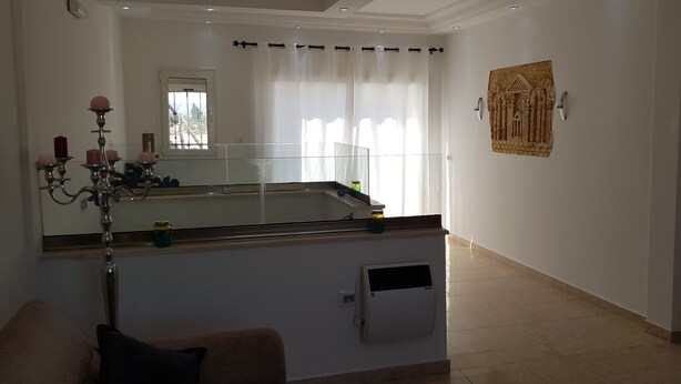 Habitació amb un mirall gran, un candelabrum, una finestra amb cortines i una obra d'art penjada a la paret.