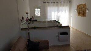 Un saló amb un sofà, una làmpada penjant, una finestra amb cortines i una obra d'art penjada a la paret.