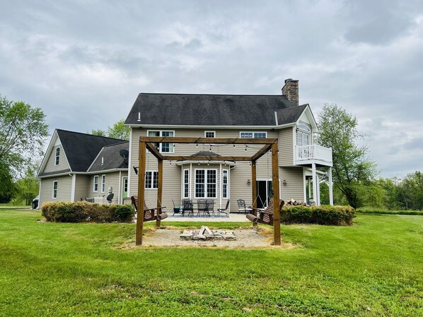 A two-story house with a covered porch, a stone chimney, and a satellite dish.