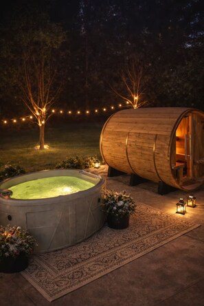 A hot tub and a wooden barrel structure with a door, surrounded by a garden with string lights and potted plants.